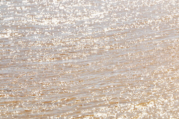 .Waves on the sunny sea coast. Magical reflections of the sun on the water, like a large number of lights. A beautiful holiday on the sea coast..