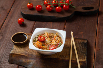 shrimp and rice yaki soba sauce next to cherry tomatoes soy sauce and chopsticks