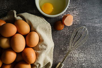 foto superior com cesta de ovos inteiros ao lado de um ovo fresco quebrado em fundo cinza com textura. sem ninguém.