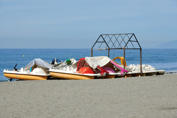 Abandoned pedal boats on the beach and covered with a tarp