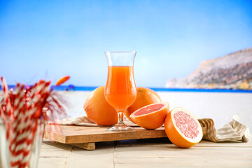 Fresh citrus fruit on wooden table top with beautiful summer landscape of calm sea and blue sky.