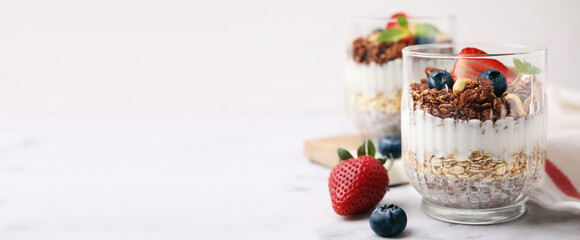 Tasty dessert with granola, yogurt, chia seeds and berries on white table. Banner design with space for text
