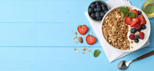 Tasty granola with blueberries, strawberry, yogurt and honey on light blue table, top view. Banner design with space for text