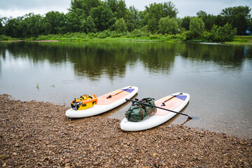 Two paddleboards are placed along the shore in preparation for a river journey. The peaceful setting encourages relaxation and exploration amidst lush greenery