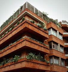 Red brick apartments building with plants growing on balconies. Barcelona, Spain