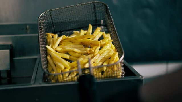 close-up in a professional kitchen the chef takes out french fries from the fryer