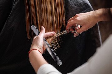 hairdresser makes a haircut to a woman in the salon. The hairdresser cuts wet hair
