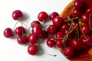 Fresh, delicious cherries spilled from a bowl on a white background