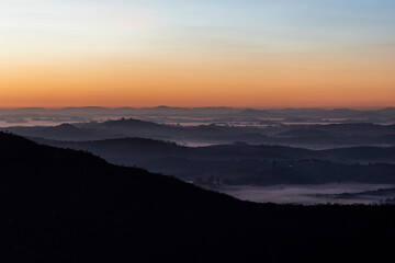 Fototapeta premium Paisagem de Camadas de montanhas com nuvens baixas no amanhecer e céu laranja