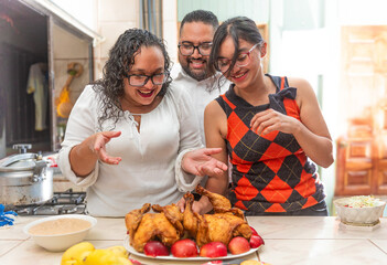Latino family members together in the kitchen, wife looking happy as she cooks dinner. 