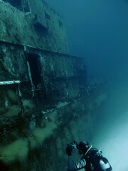 Scuba diver in the deep exloring underwater shipwreck. Underwater photographer with camera, diver...