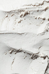 Macro shot of a white powdery texture displaying fine grains and rough patterns. This close-up captures the soft, delicate surface, making it ideal for themes related to beauty, skincare, and cosmetic