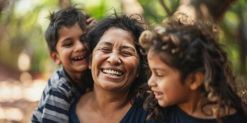 Obraz premium Happy hispanic mother laughing with children in outdoor setting