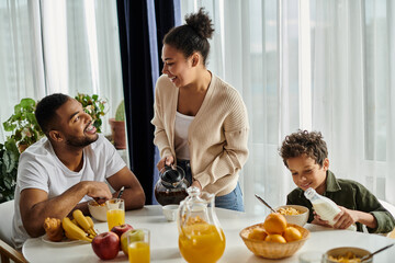 Happy African American family enjoying time together at the table with a pitcher of orange juice.