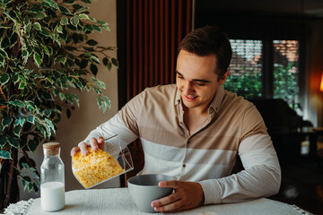 One young caucasian man is eating corn flex breakfast at home before work	