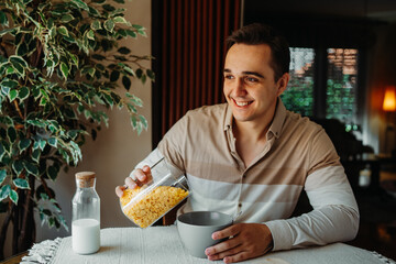 One young caucasian man is eating corn flex breakfast at home before work	