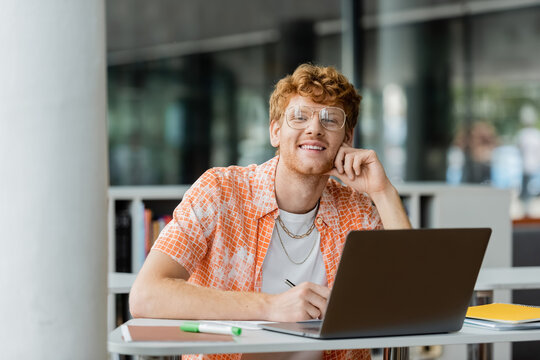 Young man engrossed in studying on his laptop at a table.