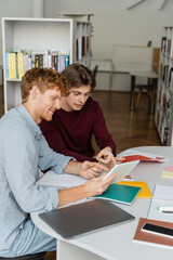 Two men engrossed in studying a book at a table.