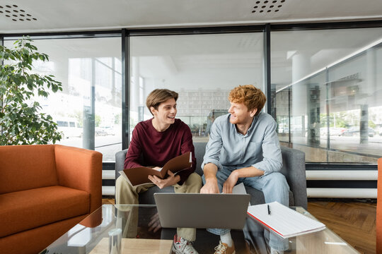 A pair of people seated on a couch in library.