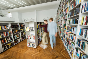Two young male students engrossed in studying together in a library.