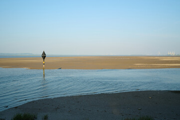 River dee estuary at low tide with single hazard marker on sunny day