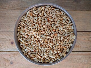 Roasted sunflower seeds kernel macro in bowl. Peeled sunflower seeds on wooden background. Eat healthy food, top view from above. Vegan cooking organic ingredient shelled salted sunflower seeds core
