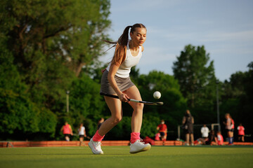Obraz premium girl hockey player plays field hockey on a sunny day, the hockey player hits the ball with a stick