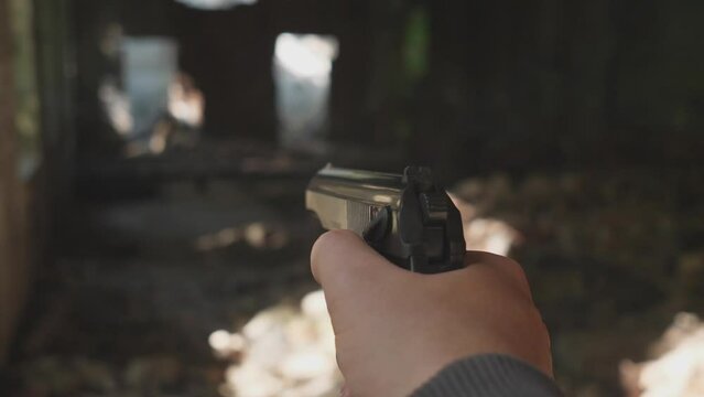 Gun in hand shooting in the forest abandoned building first person view