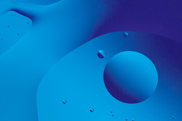 Fluid blue shapes and bubbles form an abstract, serene pattern, evoking a peaceful underwater or liquid surface.
