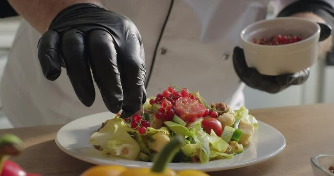 Chef serving healthy vegetable salad plate with red currant. Dish serving. Cooking process. Healthy lifestyle