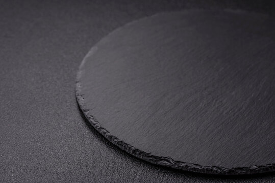Empty round slate plate for template on the black background
