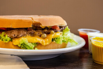 Delicious brazilian burger in a plate, with steak, cheese, lettuce, tomato, corn and peas. This...