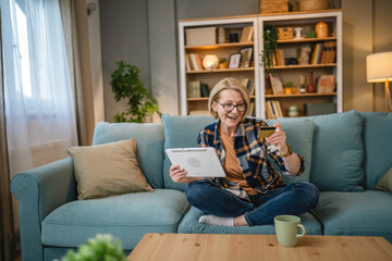 Senior woman caucasian female hold credit card online shopping at home