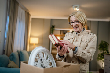 Senior woman caucasian female pack or unpack boxes with stuff moving