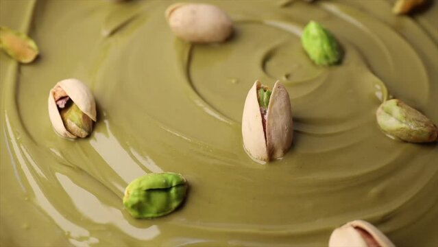 pistachio paste with pistachio nuts in a shell, rotation in circle. Pistachio cream, Turning. selective focus. green background