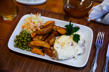 Tasty French style meat in bechamel sauce with side dish of fried potato wedges and vegetables