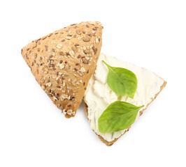 Pieces of bread with cream cheese and basil leaves isolated on white, top view