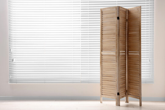 Wooden folding screen near white wall indoors, space for text