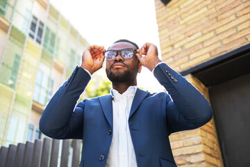Confident black businessman adjusting sunglasses outdoors