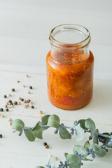 Homemade mango and cherry tomato chutney preserve on glass jar with eucalyptus twig