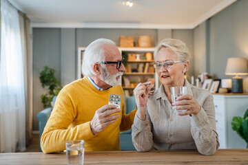 senior couple at home woman take medicine while her husband sit beside