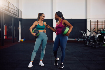 Young happy sportswomen talking while working out in health club.