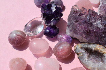 Beautiful purple druses and amethyst geodes and rose quartz stones on a pink background. Healing...