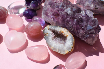 Beautiful purple druses and amethyst geodes and rose quartz stones on a pink background. Healing...