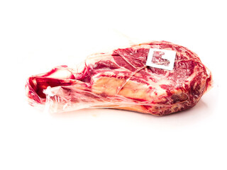Premium tomahawk steak in vacuum package with security tag. Top quality beef meat product protection from criminal act of theft and stealing. White background.