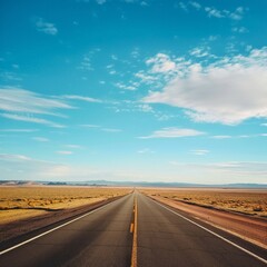 Naklejka premium Vertical shot of an empty road in the middle of a desert under a beautiful blue sky 