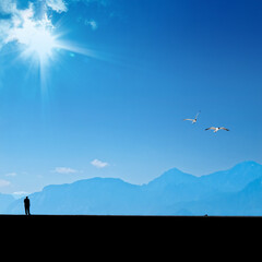 Silhouetted man standing on street over blue sky