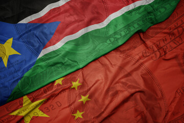 waving colorful flag of south sudan and national flag of china on the dollar money background....