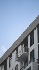 artistically framed capture of building with three balconies and multiple windows built into white and gray building