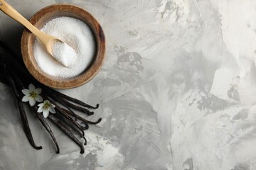 Sugar in bowl, vanilla pods and flowers on grey textured table, flat lay. Space for text